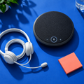 Conference speakerphone and headset on cobalt blue background